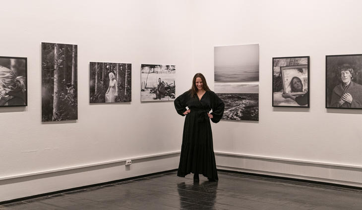 Fotograf Marina Rastad Tennefoss foran noen av bildene som er med på utstillingen "Vi trodde vi kunne fly".